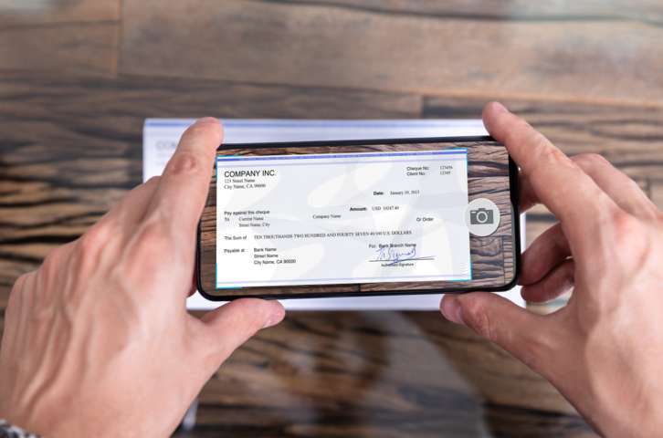 man holding a smart phone using an app to scan a check